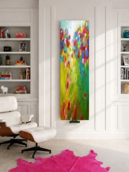 A modern enteriőr falán egy függőleges kialakítású WORLD ART radiátor látható élénk színű, kortárs festményszerű mintával és dekoratív megjelenésben.